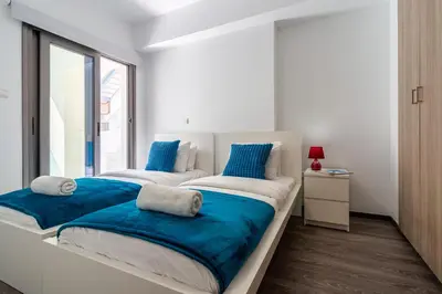 two beds in a white room with a window at Crystal 2-Bedroom Apartment in Larnaca in Larnaka
