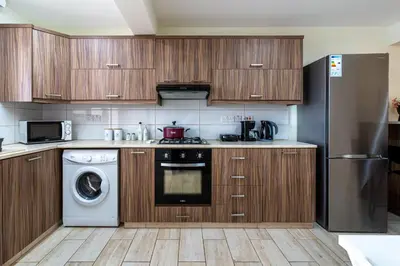 a kitchen with wooden cabinets and a washer and dryer at Celeste 3-Bedroom Apartment in Larnaca in Larnaka