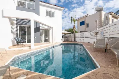 a swimming pool in front of a white house at Lindos Villa Ekaterina in Paralimni