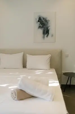a bed with white sheets and pillows in a room at Sunrise Beachfront Villas - Villa 1 in Paralimni