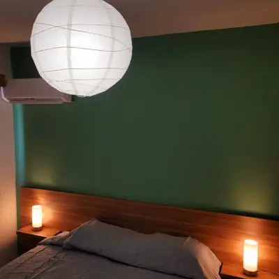 a bedroom with a green wall and a bed with two lights at Palm Sea Suite 17 in Larnaka