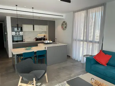 a kitchen and living room with a blue couch at Gaia Seaview Apartment 1 in Larnaka