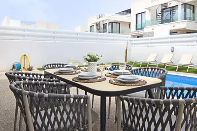 a table and chairs on a patio with a pool at Villa Queen Alexandra in Protaras