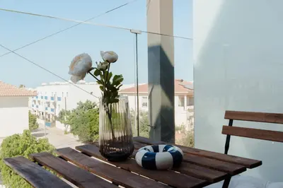 a vase with flowers on a wooden table on a balcony at Mythical Spa Suite - GYM*Yoga Room*Pools in Protaras