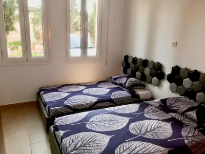 two beds in a room with two windows at Villa Poseidon in Pervolia