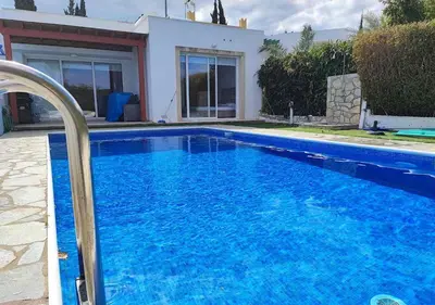 a large blue swimming pool in front of a house at Villa Poseidon in Pervolia