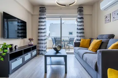 a living room with a couch and a tv and a table at Vox 2-Bedroom Apartment in Larnaca in Larnaka