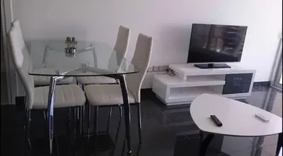 a glass table with four chairs and a television at Ayia Napa Luxury Apartment in Ayia Napa