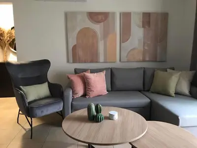 a living room with a couch and a table and a chair at Pebble in Protaras