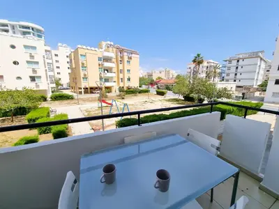 a white table on a balcony with a view of buildings at Seaside Heaven Apartment With Pool in Larnaka