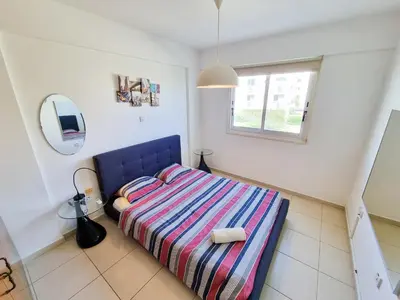 a bedroom with a bed with a striped blanket and a mirror at Seaside Heaven Apartment With Pool in Larnaka