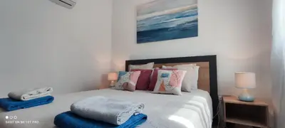 a bedroom with a white bed with pillows and a blue lamp at Seaview Harmony in Larnaka