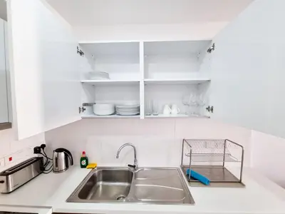 a kitchen counter with a sink and white cabinets at Sea Bay Apartment in Larnaka