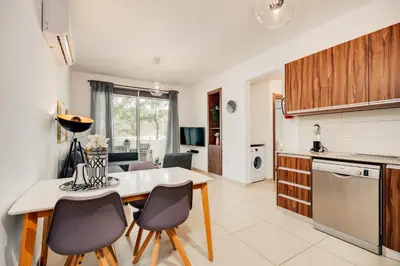 a kitchen and living room with a table and chairs at SunnyVillas: 2BR Mythical Apt*Swimming Pool*AK04 in Paralimni