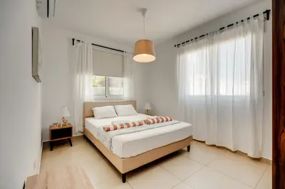 a white bedroom with a bed and a window at SunnyVillas: 2BR Mythical Apt*Swimming Pool*AK04 in Paralimni