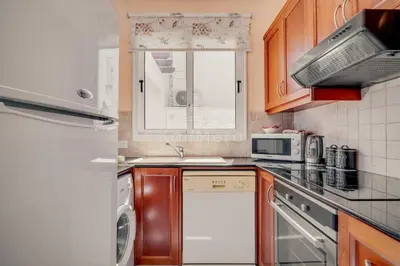 a kitchen with wooden cabinets and a white appliance at Villa Sunrise Pernera in Paralimni