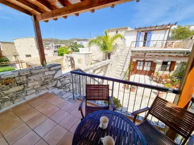 a balcony with two chairs and a view of a building at Poseidon's Pool Paradise in Skarinou