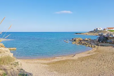 a beach with rocks and the ocean on a clear day at Villa Dina in Protaras