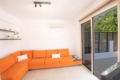an orange couch in a living room with a sliding glass door at Sunny Side Up Villa in Protaras