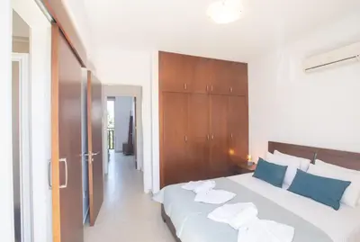 a bedroom with a large white bed with blue pillows at Sunny Side Up Villa in Protaras