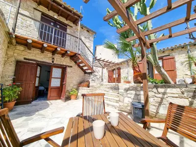 a patio with a wooden table and chairs in front of a building at Aphrodite's Pool Retreat in Skarinou