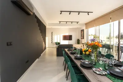 a dining room with a long table with green chairs at Tsiolakki Homes Luxury Villas in Protaras