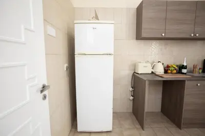 a white refrigerator in a kitchen with a counter at Aladdin's Hostel in Larnaka