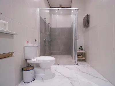 a white bathroom with a shower and a toilet at Maestro Sea - View Apartment in Larnaka