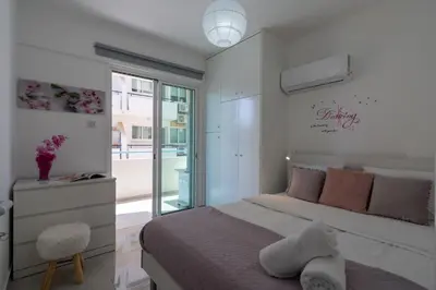a white bedroom with a bed and a window at Andrea 3-Bedroom Apt in Mackenzie in Larnaka